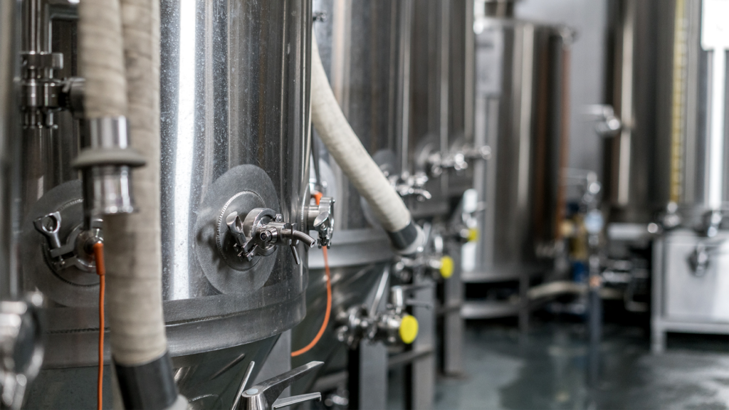A row of stainless steel fermentation tanks in a brewery.