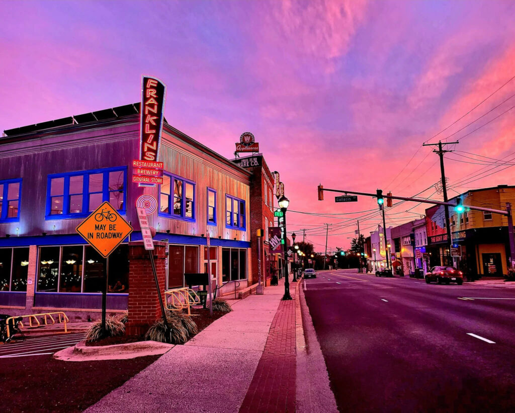 A street corner in front of Franklin’s Restaurant and General Store under a vibrant pink and purple sunset.